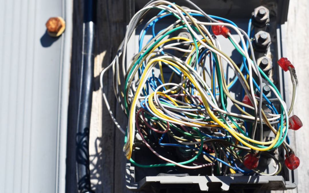 Messy electrical wiring inside a junction box, highlighting the dangers of DIY electrical repairs and the importance of hiring certified electricians for safe installations.