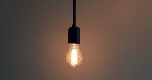 Hanging light bulb emitting warm glow, symbolizing energy conservation and efficient lighting solutions for reducing electricity usage.