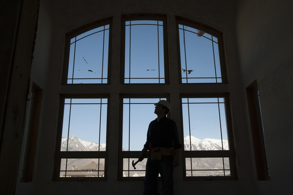 Electrician inspecting large windows in a home with mountain view, emphasizing electrical safety and preparedness for hurricane season.