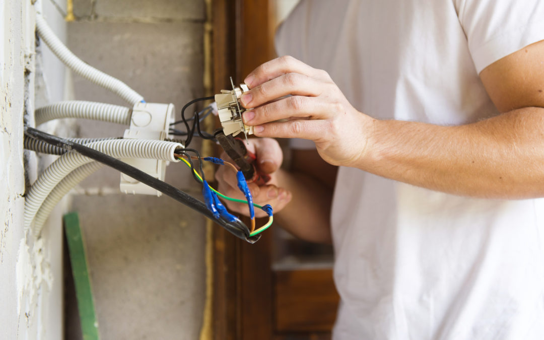 Electrician working on electrical wiring installation, showcasing tools and connections, emphasizing the importance of hiring qualified electrical contractors for safety and compliance in residential and commercial settings.