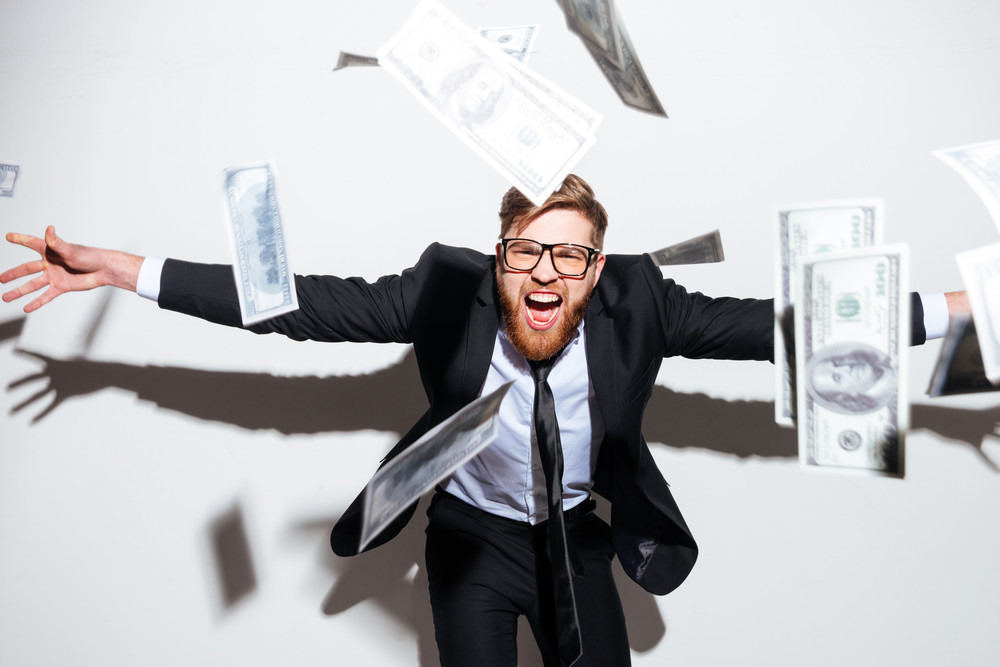 Man in a suit celebrating with money flying around him, symbolizing financial success and savings, relevant to tips on reducing electricity bills.