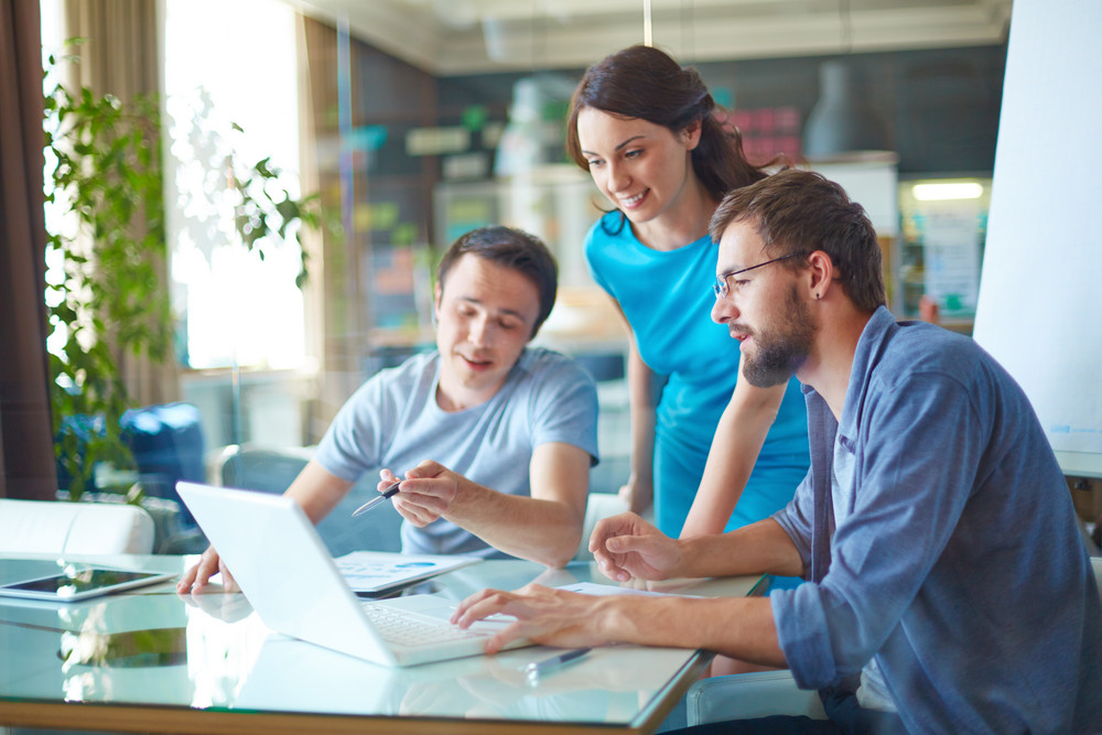 Three professionals collaborating in an office setting, reviewing documents and discussing business electrical needs, emphasizing teamwork and planning for future growth.