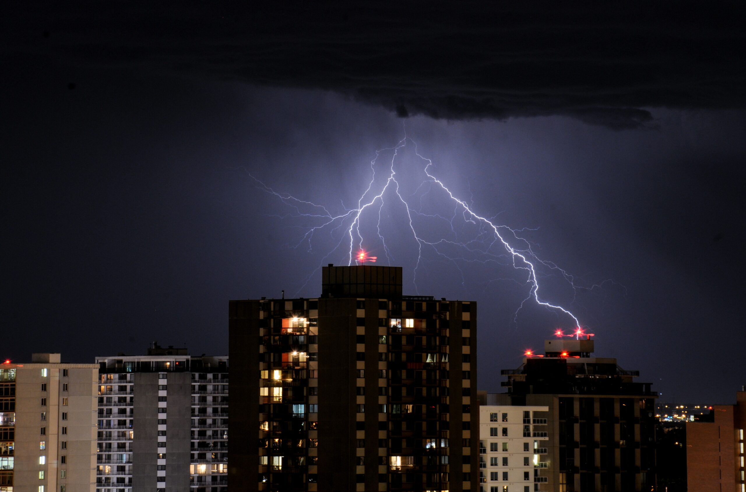 Lightning striking buildings at night, illustrating the risks of electrical surges and the importance of lightning arresters for protection.