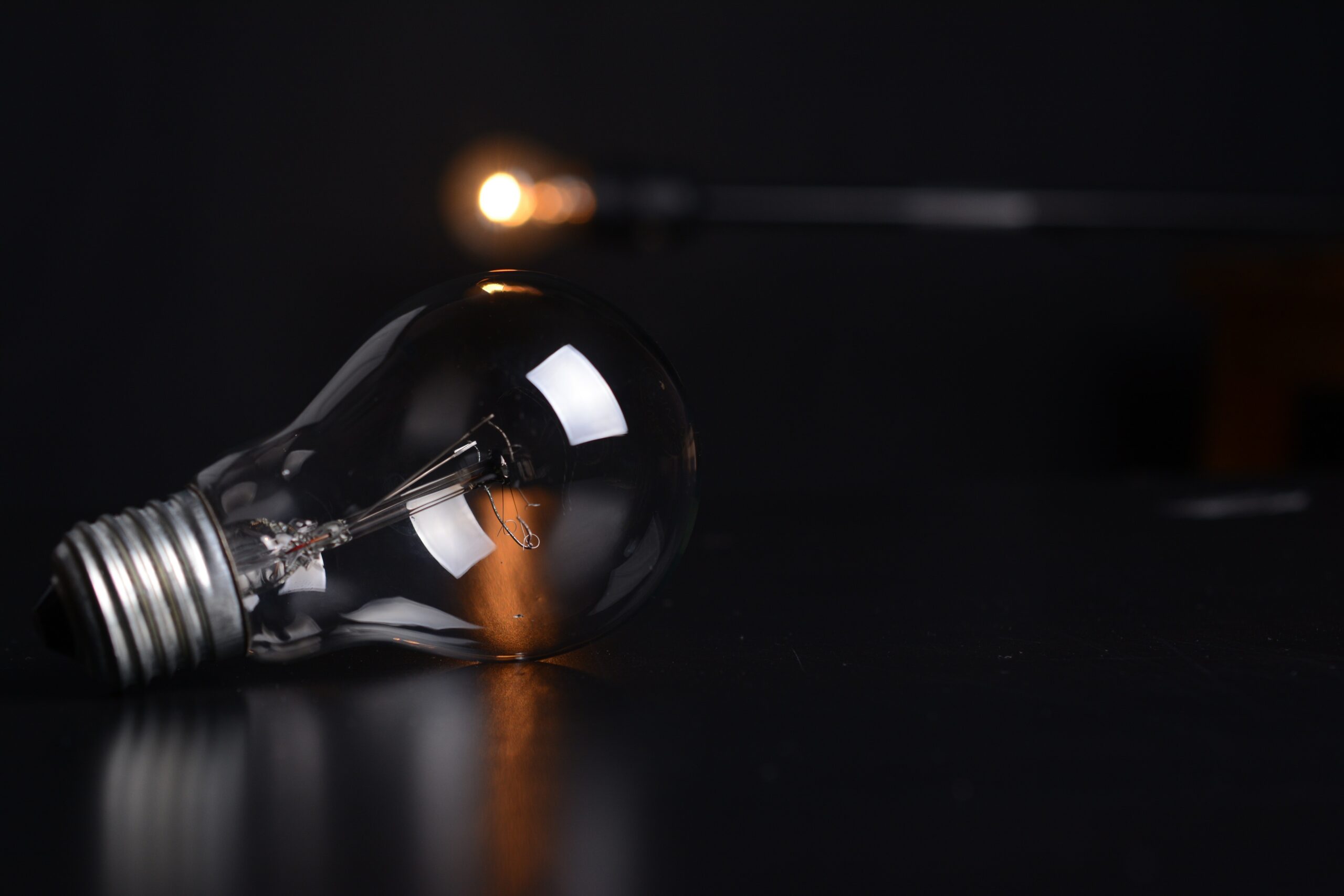 Light bulb on a dark surface, symbolizing energy efficiency and electric services, relevant to summer energy-saving tips by Kazar's Electric.