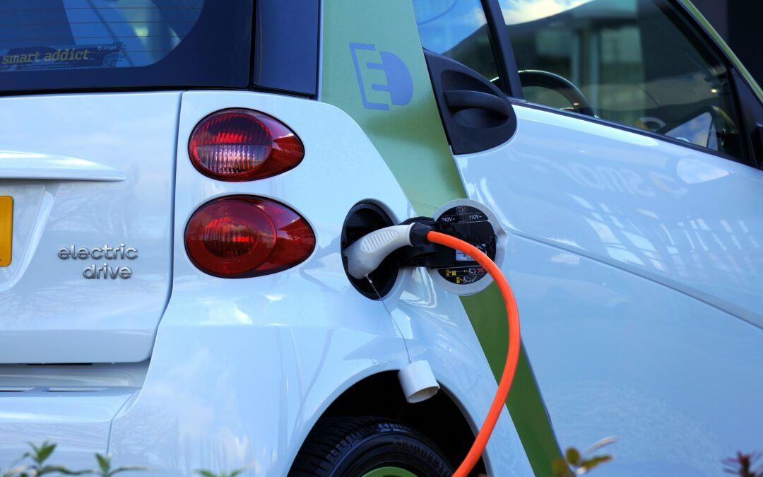 Electric vehicle charging station with an orange charging cable connected to a white car labeled "electric drive," illustrating home EV charger preparation.