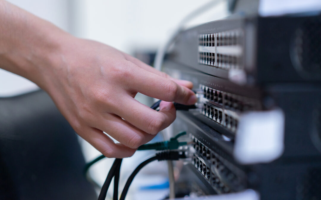 Hand connecting cables to commercial electrical switches, emphasizing maintenance and safety checks in industrial settings.