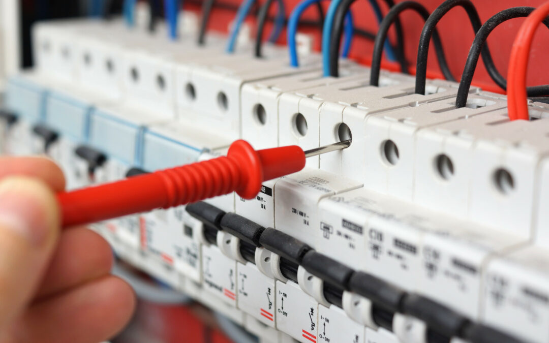 Red multimeter probe testing electrical circuit breakers in a residential electrical panel, emphasizing the importance of electrical safety inspections in Tampa.