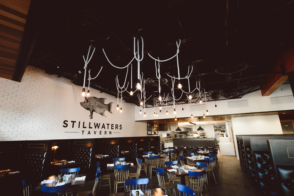 Interior of Stillwaters Tavern featuring unique light fixtures, blue chairs, and a modern design; emphasizes the importance of reliable electrical systems for restaurant operations.