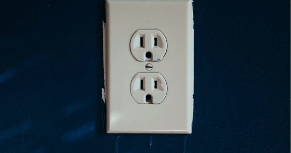 Electrical outlet on a dark blue wall, relevant to emergency electrician services and electrical safety.