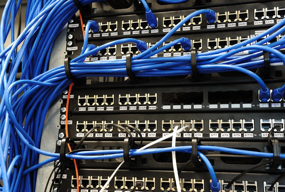 Network cables and ports in a structured wiring panel, illustrating the complexity of electrical systems and the importance of professional installation for safety.