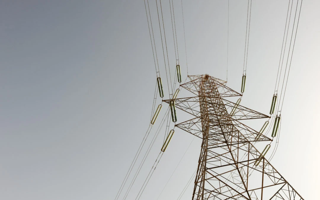 Power transmission tower with electrical lines, illustrating the importance of surge protection for business electrical systems, as discussed by Kazar's Electric.