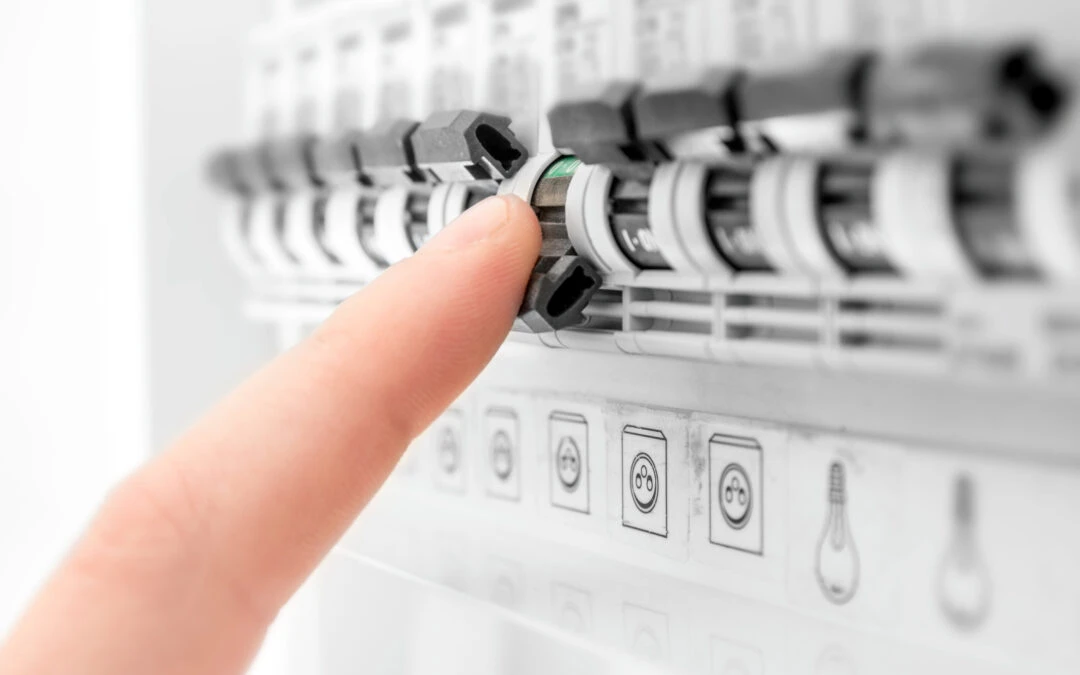 Finger adjusting a transfer switch on an electrical panel, illustrating the transition to backup power during outages.