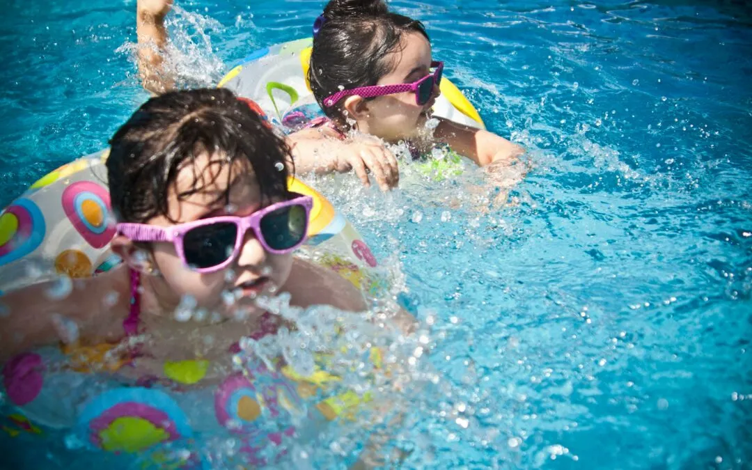 Two children swimming in a pool with inflatable rings, showcasing Kazar's Electric's focus on pool safety.