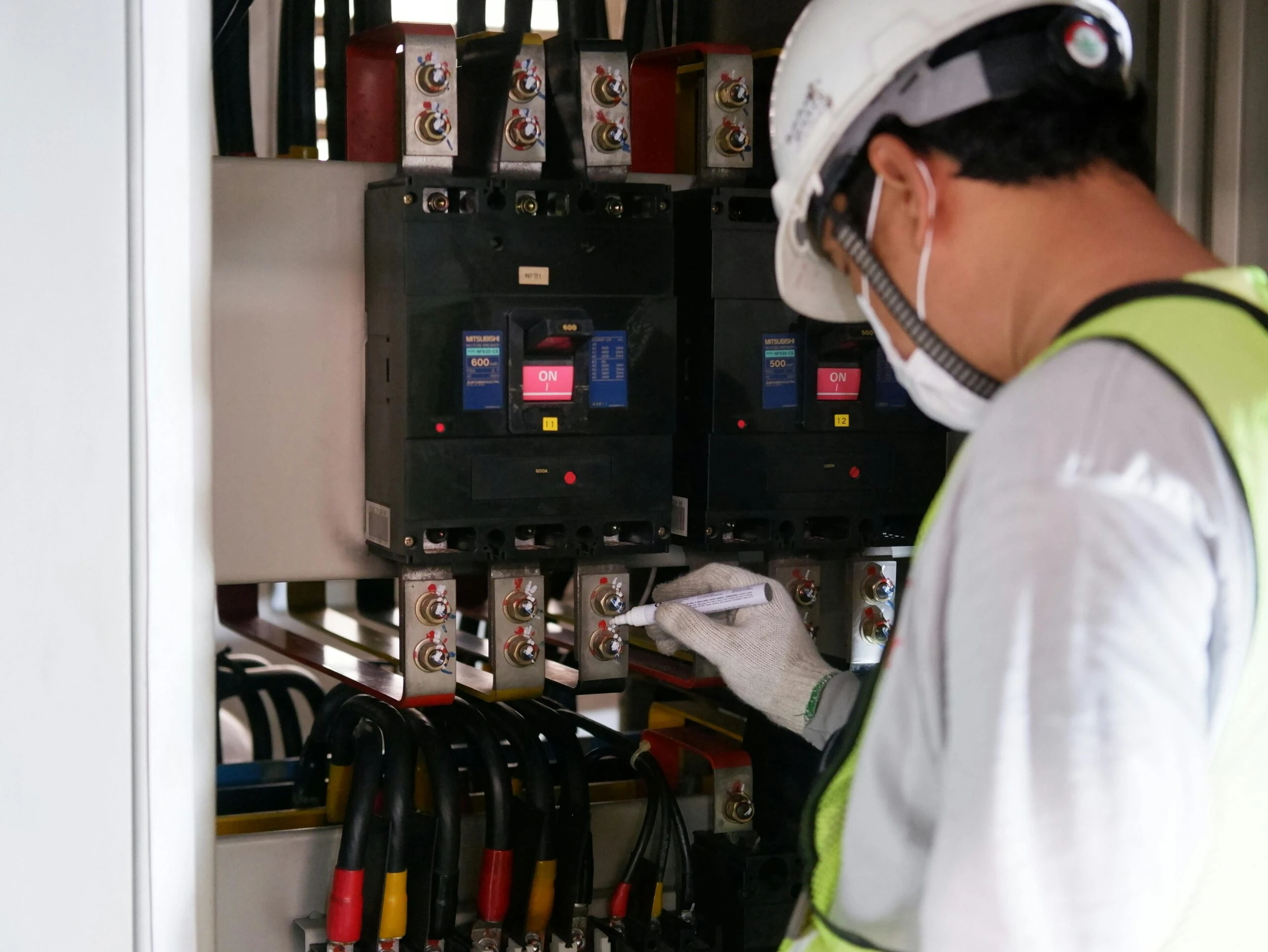 Electrical technician inspecting control panel with safety gear at Kazar’s Electric for generator installation compliance.